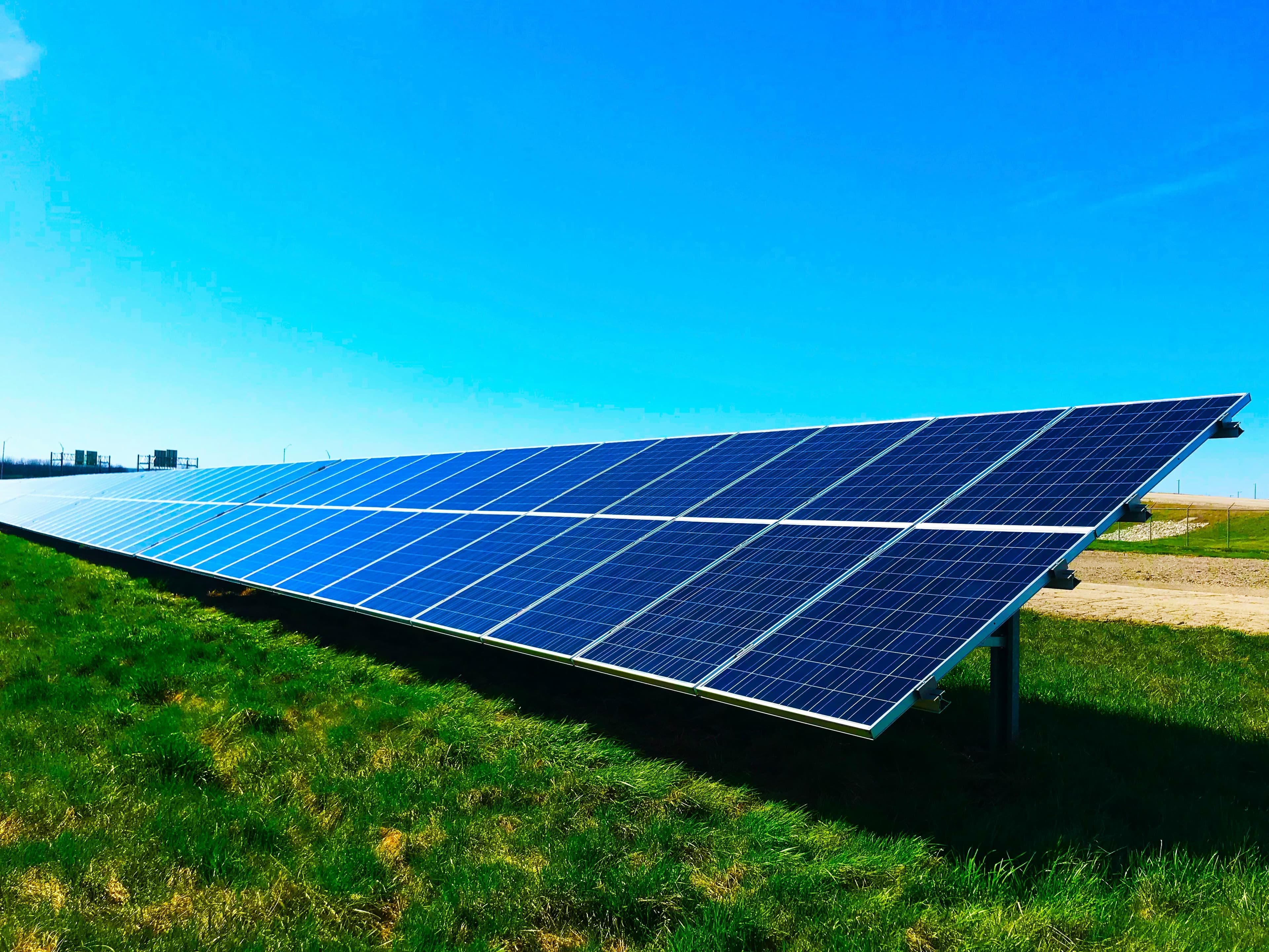 A field of solar panels under a bright blue sky